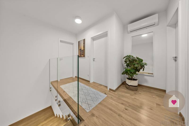 ROVINKA-Prenájom modernej, zariadenej novostavby 4 izbového rod.domu - Chodba v 4-izbovom byte s podlahou s dreveným dekorom, zrkadlom a kvetinou.