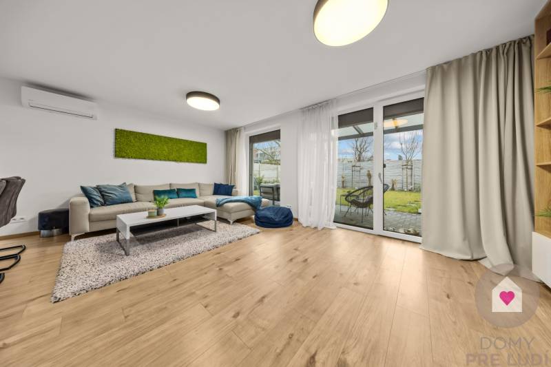 ROVINKA-Prenájom modernej, zariadenej novostavby 4 izbového rod.domu - Obývacia izba so sedačkou, presklenými dverami a podlahou s dreveným dekorom v 4-izbovom byte.