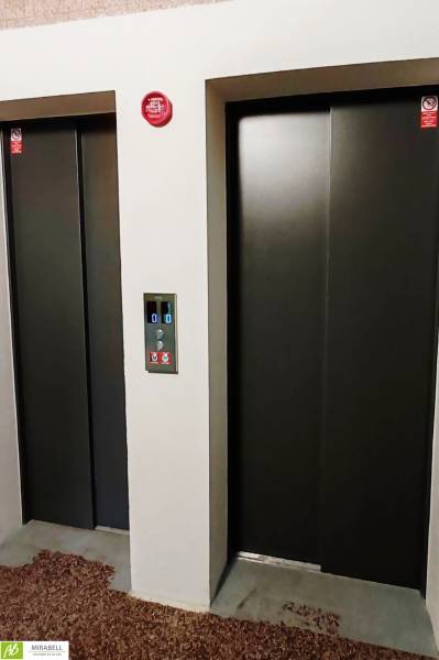 3 izbový byt pri električkovej trati s výhľadom na Draždiak - Dva výťahy s kovovými dverami a ovládacím panelom medzi nimi.