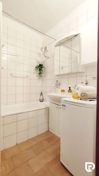 | 2-izbový byt 68m2, Štvrť SNP | Trenčianske Teplice  - Kúpeľňa v 2-izbovom byte so sprchou, umývadlom a práčkou, svetlé obklady.