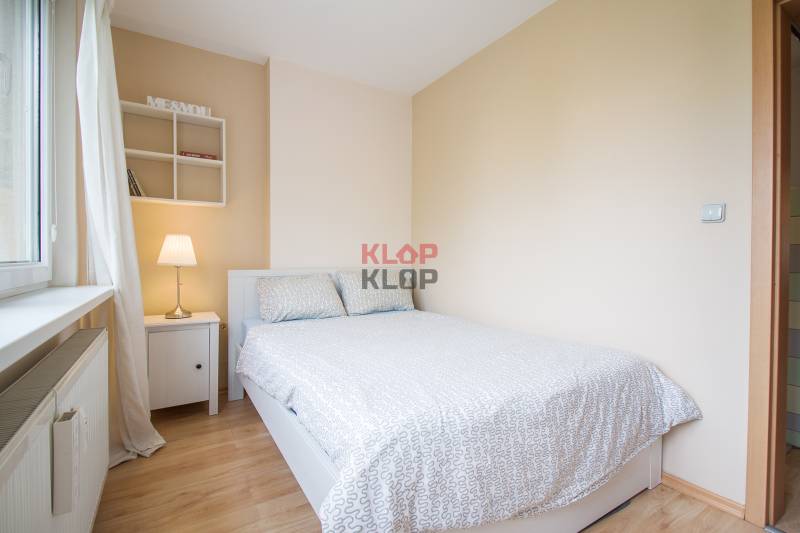 Pozrite si PRÍJEMNÝ 2i byt so ZARIADENÍM, LODŽIOU a KLIMATIZÁCIOU - Spálňa so svetlou stenou a posteľou, vedľa okna je nočný stolík s lampou.