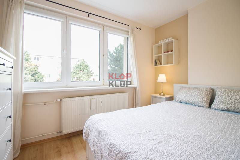 Pozrite si PRÍJEMNÝ 2i byt so ZARIADENÍM, LODŽIOU a KLIMATIZÁCIOU - Svetlá spálňa s posteľou, bielym nábytkom a podlahou s dreveným dekorom v 2-izbovom byte.