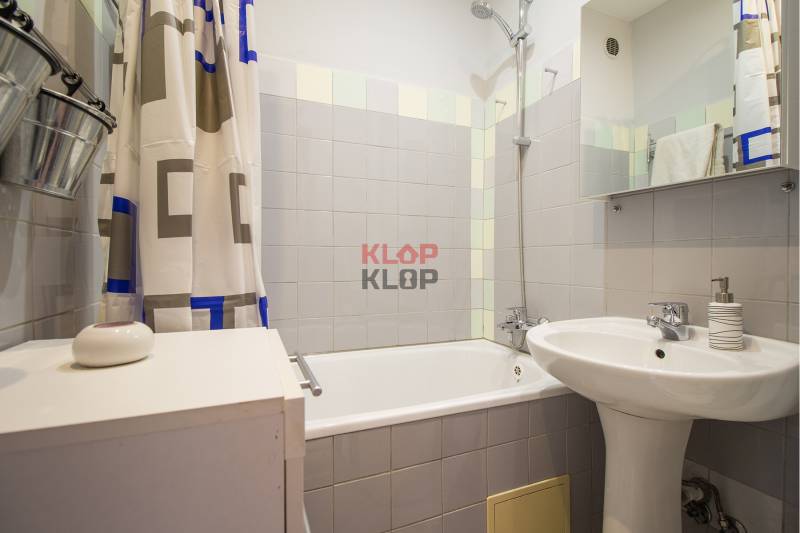 Pozrite si PRÍJEMNÝ 2i byt so ZARIADENÍM, LODŽIOU a KLIMATIZÁCIOU - Kúpeľňa s vaňou, závesom, umývadlom a bielymi obkladačkami v 2-izbovom byte.