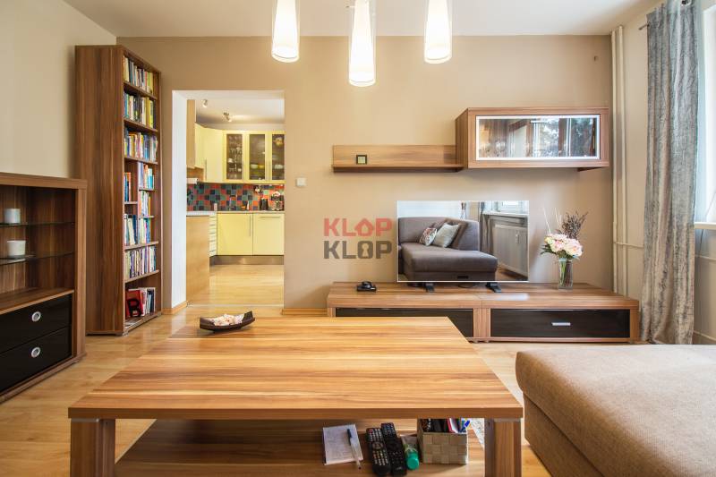 Pozrite si PRÍJEMNÝ 2i byt so ZARIADENÍM, LODŽIOU a KLIMATIZÁCIOU - Obývačka 2-izbového bytu s podlahou s dreveným dekorom, nábytkom a výhľadom do kuchyne.