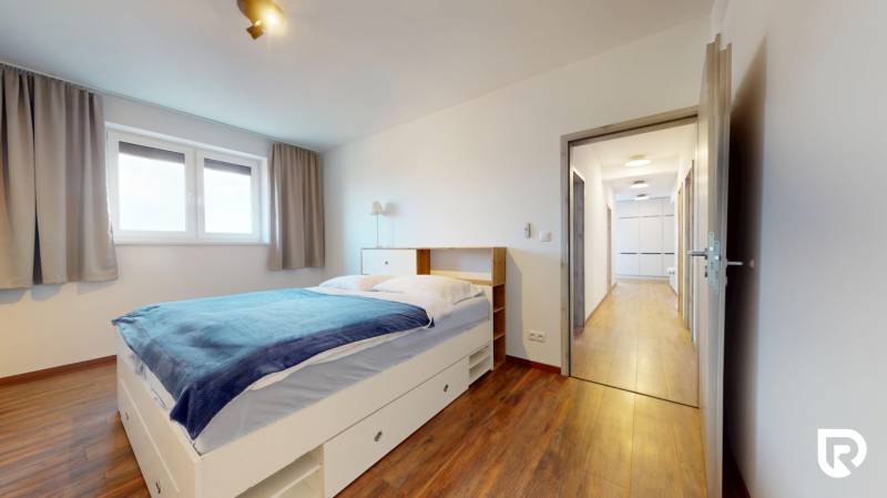 | Exkluzívny 4-izbový byt s obrovskou terasou | Stupava - Spálňa s posteľou a podlahou s dreveným dekorom v 4-izbovom byte.