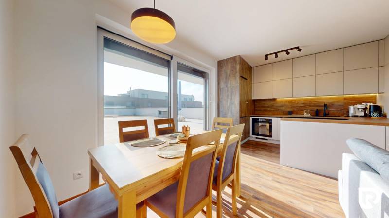 | Exkluzívny 4-izbový byt s obrovskou terasou | Stupava - Jedáleň a kuchyňa v 4-izbovom byte s podlahou s dreveným dekorom.