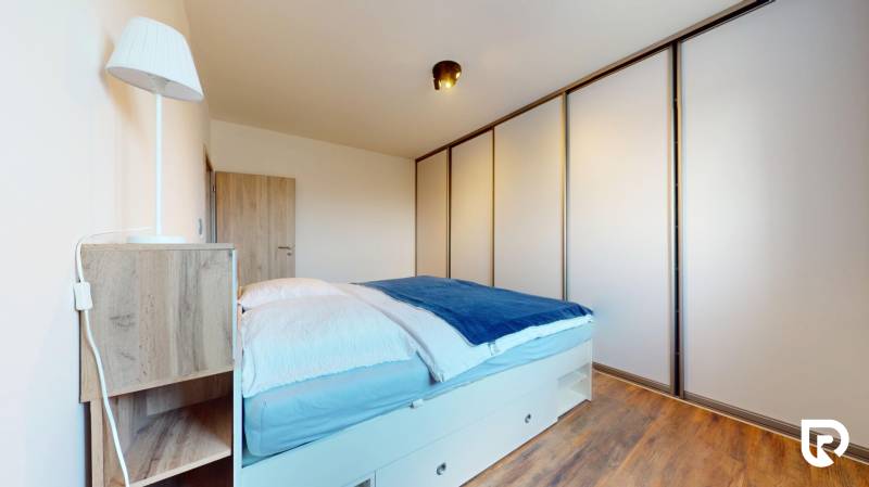 | Exkluzívny 4-izbový byt s obrovskou terasou | Stupava - Spálňa v 4-izbovom byte s veľkou skriňou a podlahou s dreveným dekorom.