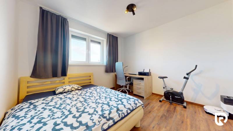 | Exkluzívny 4-izbový byt s obrovskou terasou | Stupava - Spálňa v 4-izbovom byte s posteľou, pracovným stolom a podlahou s dreveným dekorom.