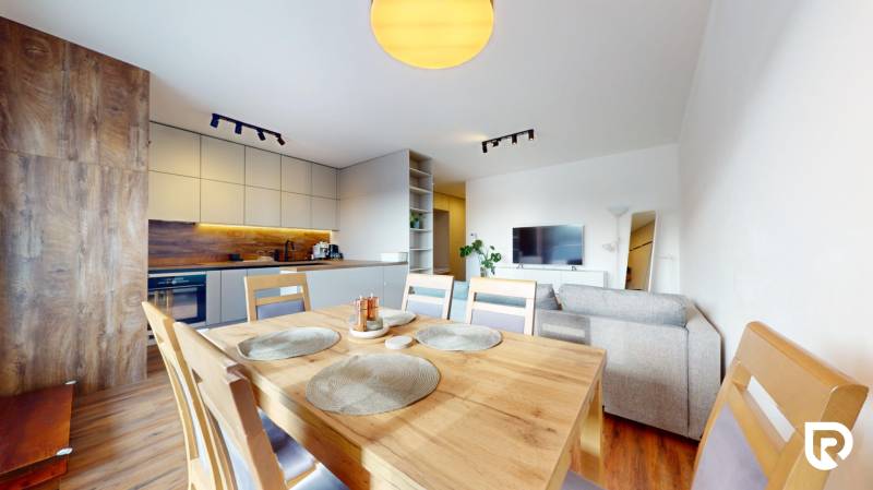 | Exkluzívny 4-izbový byt s obrovskou terasou | Stupava - Jasná kuchyňa s jedálňou a pohovkou v 4-izbovom byte, podlaha s dreveným dekorom.