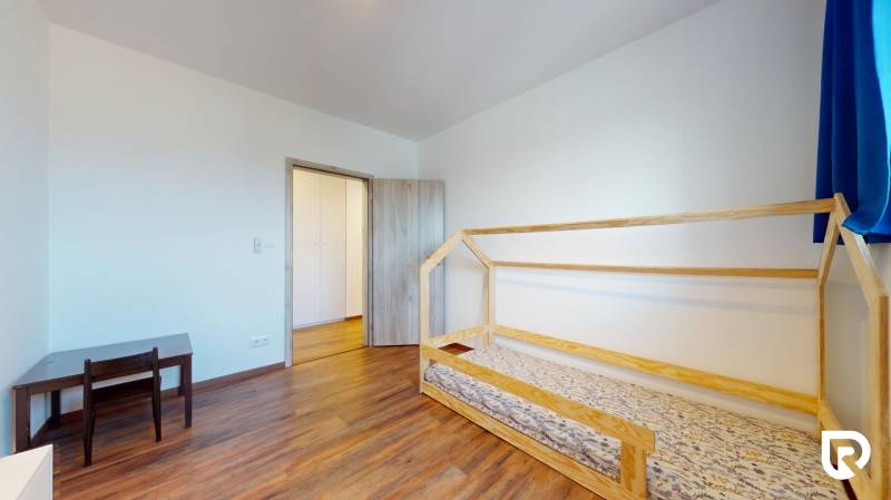 | Exkluzívny 4-izbový byt s obrovskou terasou | Stupava - Detská izba so svetlými stenami, dreveným dekorom podlahy a jednoduchým nábytkom v 4-izbovom byte.