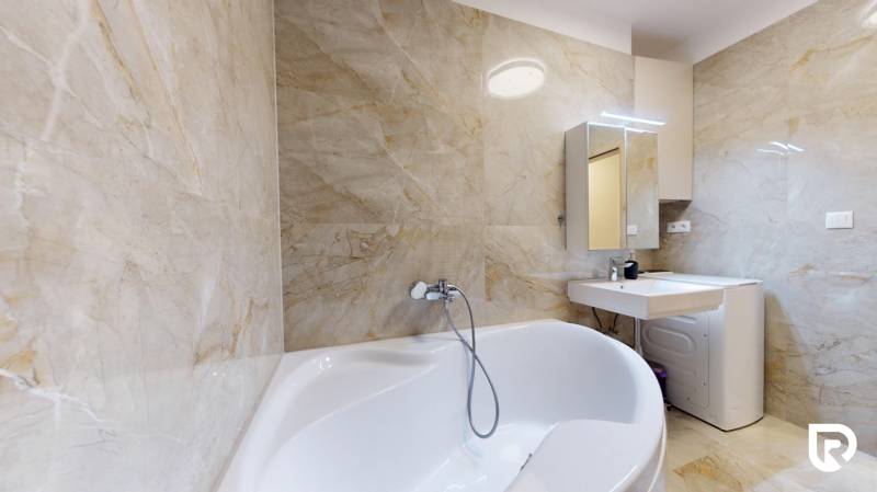 | Exkluzívny 4-izbový byt s obrovskou terasou | Stupava - Kúpeľňa s vaňou a umývadlom v 4-izbovom byte, svetlé mramorové obklady.