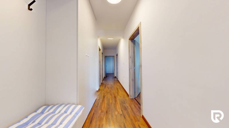 | Exkluzívny 4-izbový byt s obrovskou terasou | Stupava - Chodba v 4-izbovom byte s podlahou s dreveným dekorom a bielymi stenami.