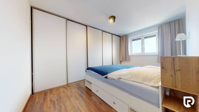 | Exkluzívny 4-izbový byt s obrovskou terasou | Stupava - Spálňa s posteľou, skriňou a podlahou s dreveným dekorom v 4-izbovom byte.