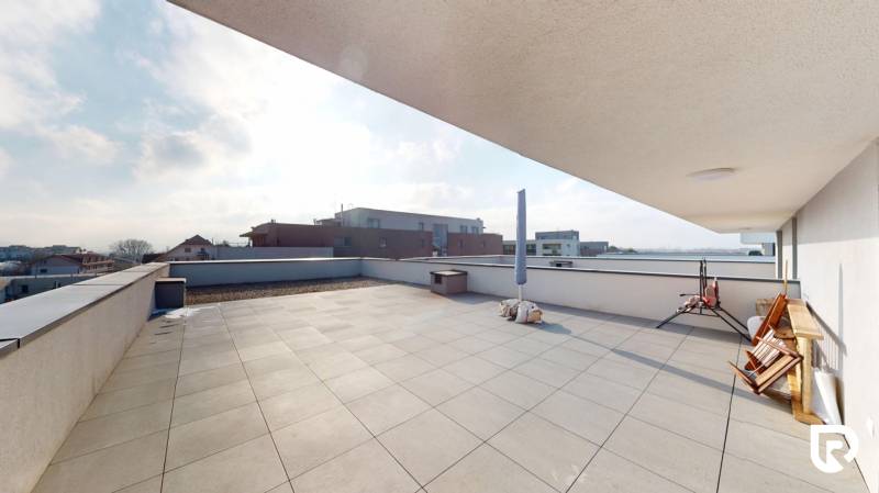 | Exkluzívny 4-izbový byt s obrovskou terasou | Stupava - Priestranná terasa 4-izbového bytu na Cementárenskej ulici v Stupave s výhľadom na okolité budovy.