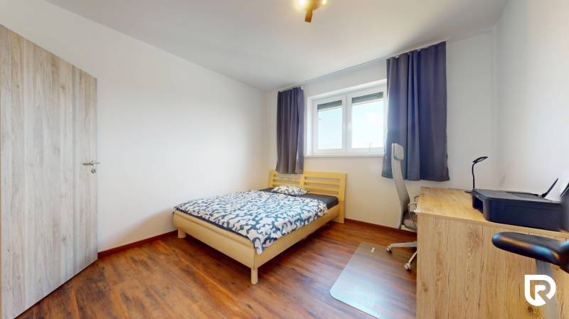 | Exkluzívny 4-izbový byt s obrovskou terasou | Stupava - Spálňa v 4-izbovom byte s dreveným dekorom, jednoduchý nábytok a pracovný stôl.