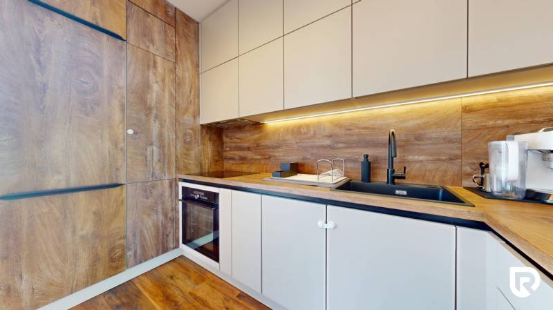 | Exkluzívny 4-izbový byt s obrovskou terasou | Stupava - Kuchyňa v 4-izbovom byte so skrinkami a podlahou s dreveným dekorom.