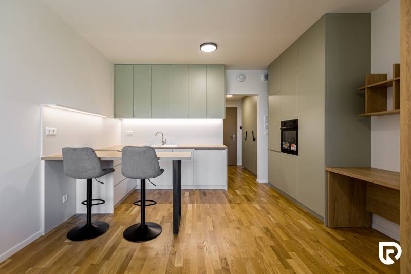 REZERVOVANÉ I METROPOLIS I Luxusný 1i byt I Staré Mesto - Kuchyňa v 1-izbovom byte so svetlou linkou a podlahou s dreveným dekorom.