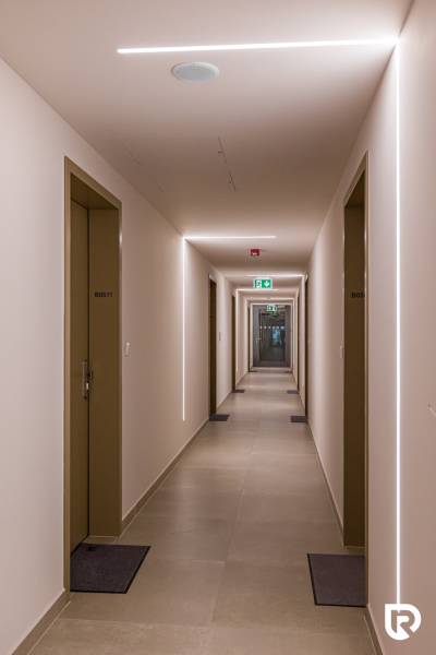 REZERVOVANÉ I METROPOLIS I Luxusný 1i byt I Staré Mesto - Koridor budovy s rovnými stenami, dverami a osvetlením, pripomínajúci hotelový interiér.