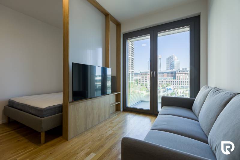 REZERVOVANÉ I METROPOLIS I Luxusný 1i byt I Staré Mesto - 1-izbový byt s podlahou s dreveným dekorom, oddelenou posteľou, sedačkou a veľkým oknom.