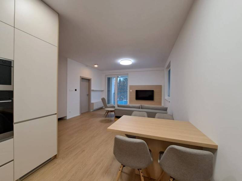 Prenájom: Lukratívny 2-izbový byt v Poprade na Novom nábreží - Obývacia izba v 2-izbovom byte s podlahou s dreveným dekorom a otvorenou kuchyňou.