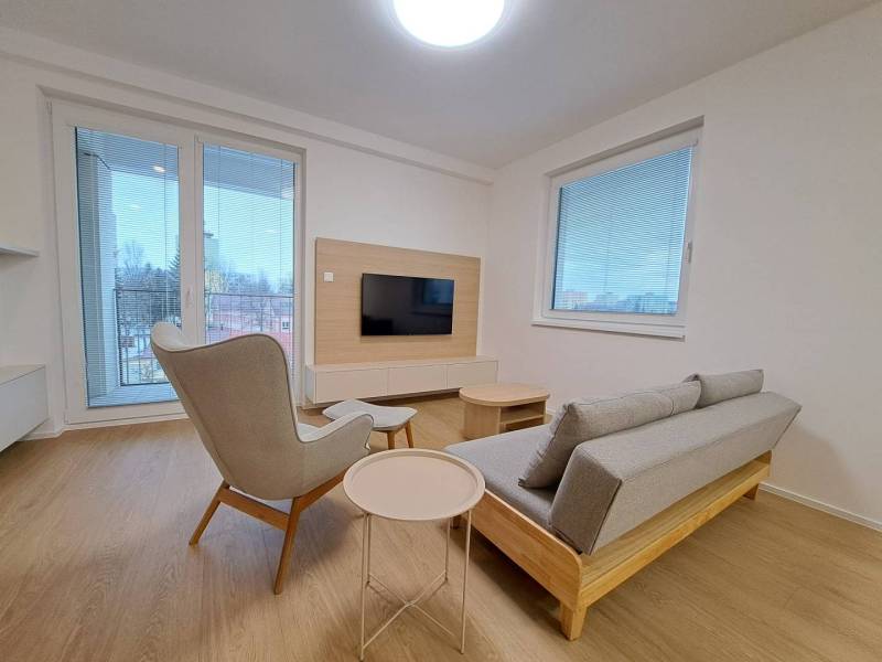 Prenájom: Lukratívny 2-izbový byt v Poprade na Novom nábreží - Obývačka v 2-izbovom byte s podlahou s dreveným dekorom, sivou sedačkou a pohodlným kreslom.