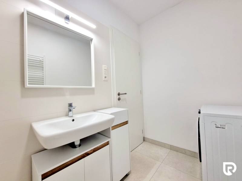 Pekný a moderný 3-izbový byt I Arboria Trnava - Kúpeľňa v 3-izbovom byte s umývadlom a práčkou, svetlé obklady na stenách.