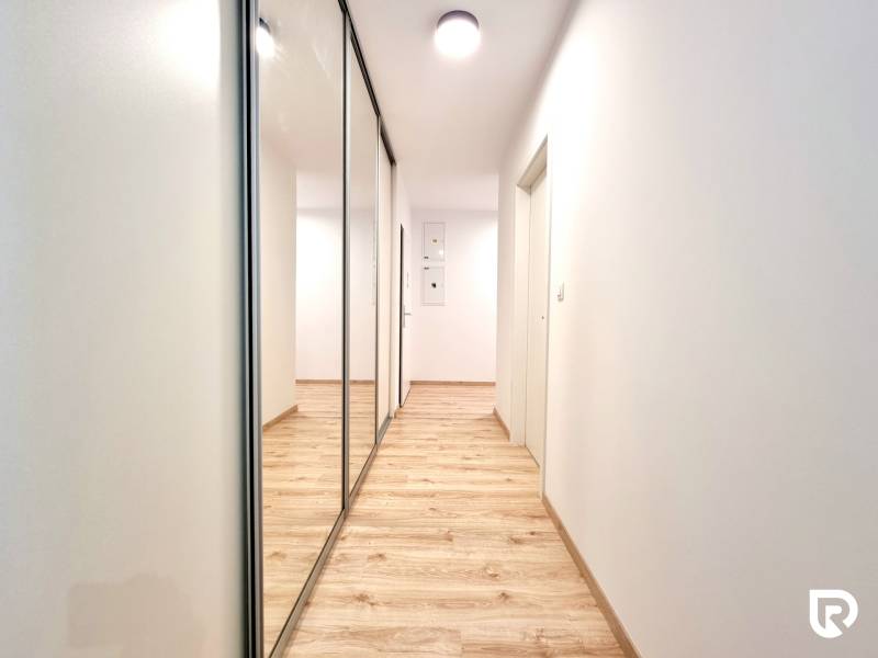 Pekný a moderný 3-izbový byt I Arboria Trnava - Chodba v 3-izbovom byte s podlahou s dreveným dekorom a zrkadlovou skriňou.