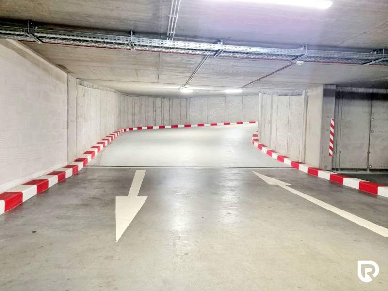 Pekný a moderný 3-izbový byt I Arboria Trnava - Podzemná garáž v Trnave na Veterná, so šípkami a červeno-bielym značením pre auta.