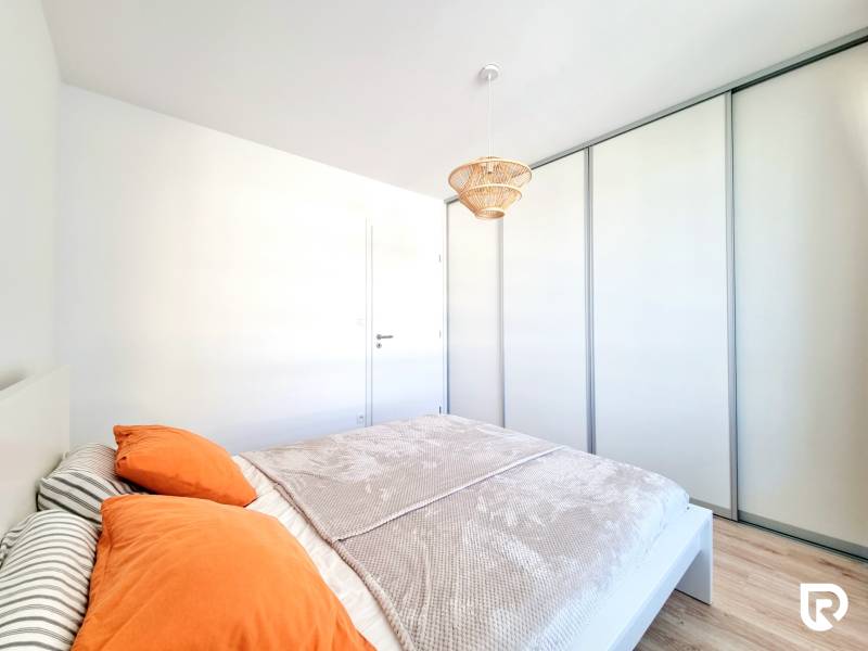 Pekný a moderný 3-izbový byt I Arboria Trnava - Spálňa v 3-izbovom byte s posuvnými skriňami a podlahou s dreveným dekorom.