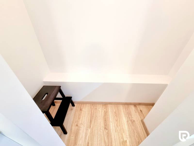 Pekný a moderný 3-izbový byt I Arboria Trnava - Malý biely priestor s dreveným dekorom a tmavým stolíkom v 3-izbovom byte.