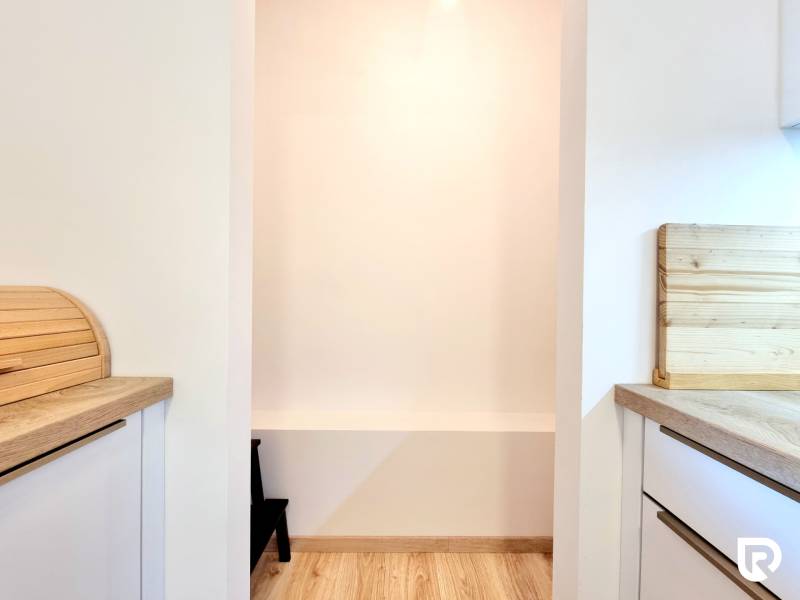 Pekný a moderný 3-izbový byt I Arboria Trnava - Kuchyňa v 3-izbovom byte s podlahou s dreveným dekorom a svetlými stenami.