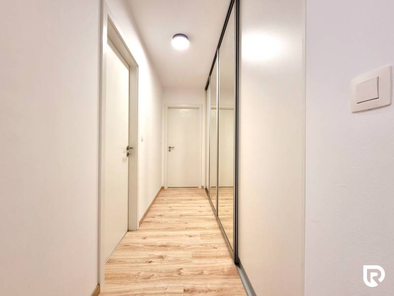 Pekný a moderný 3-izbový byt I Arboria Trnava - Chodba v 3-izbovom byte so vstavanou skriňou a podlahou s dreveným dekorom.