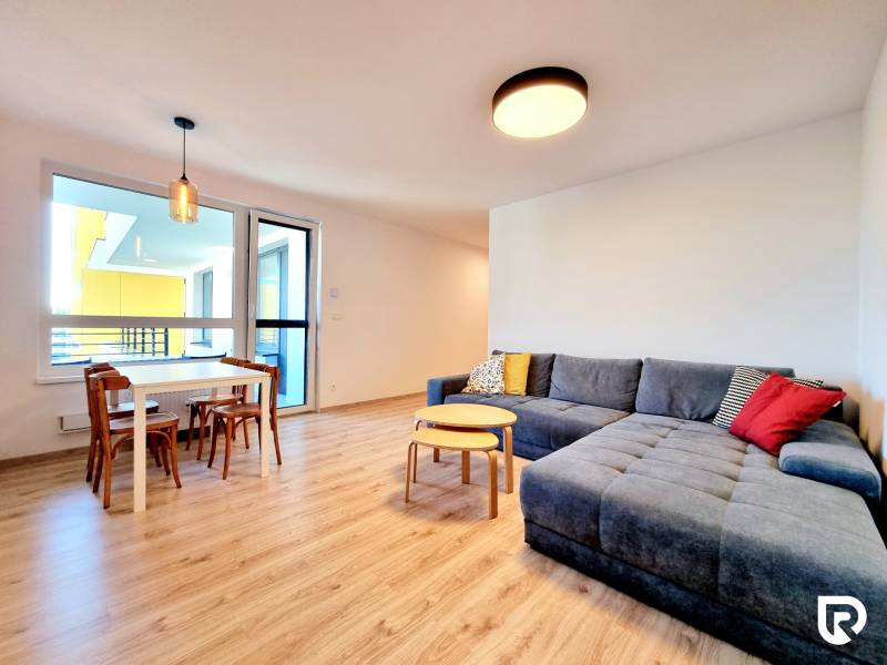 Pekný a moderný 3-izbový byt I Arboria Trnava - Obývačka 3-izbového bytu s podlahou s dreveným dekorom, sedačkou a jedálenským stolom.