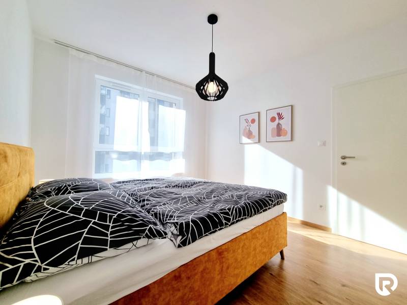 Posledný investičný krásny 2-izbový byt | 62 m² | RÍNOK RAČA - Spálňa s dvojlôžkom, bielymi závesmi a podlahou s dreveným dekorom v 2-izbovom byte.