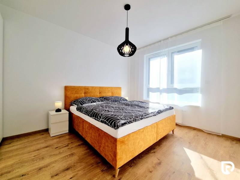 Posledný investičný krásny 2-izbový byt | 62 m² | RÍNOK RAČA - Spálňa v 2-izbovom byte s posteľou, nočným stolíkom a podlahou s dreveným dekorom.