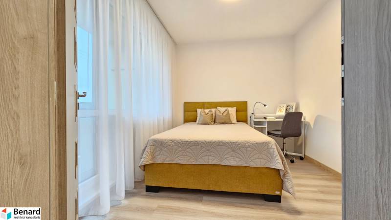 Moderný unikát - 1,5- izb. byt s 2 loggiami na prenájom (Nad jazerom) - Spálňa v 1-izbovom byte s posteľou, písacím stolom a podlahou s dreveným dekorom.