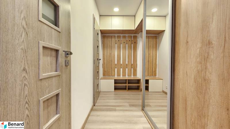 Moderný unikát - 1,5- izb. byt s 2 loggiami na prenájom (Nad jazerom) - Interiér 1-izbového bytu s podlahou s dreveným dekorom, skriňami a vešiakovou stenou.