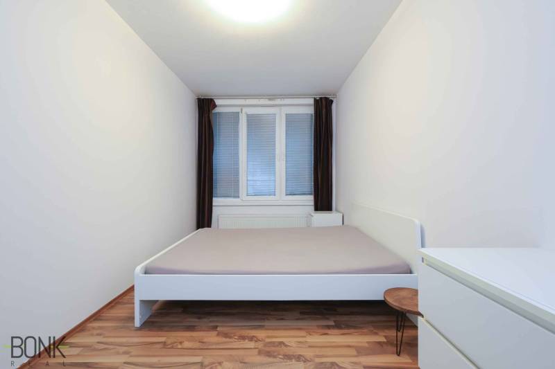 Predaj útulný 2 izbový byt, novostavba, super lokalita Jégeho ulica. - Spálňa v 2-izbovom byte s bielym nábytkom a podlahou s dreveným dekorom.