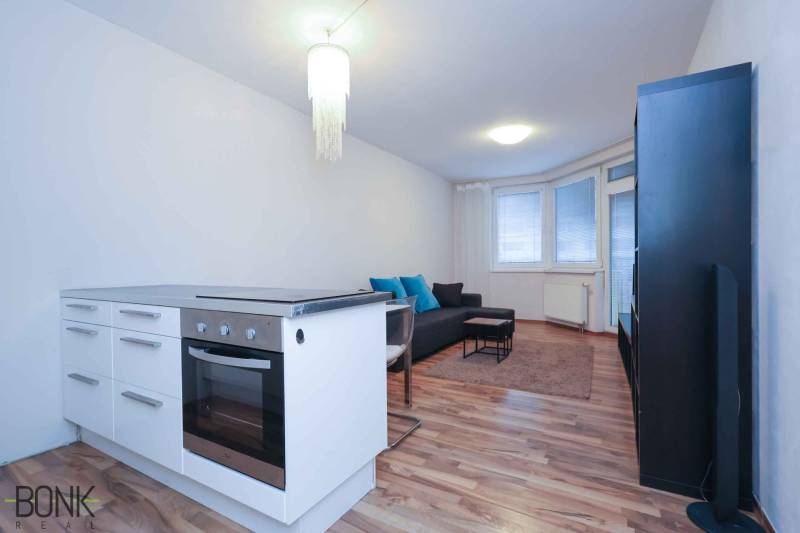 Predaj útulný 2 izbový byt, novostavba, super lokalita Jégeho ulica. - Kuchynský kútik a obývacia izba v 2-izbovom byte so sporákom a pohovkou.