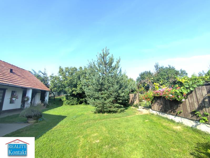 Ponúkame na predaj záhradný domček - Jasová - Záhrada rodinného domu v Jasovej s trávnikom, stromami a kvetmi.