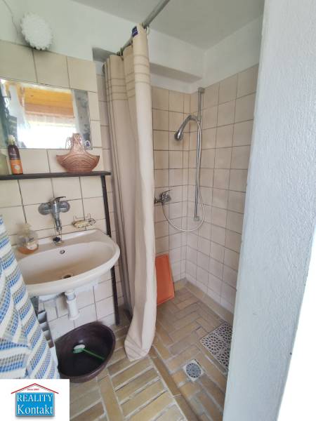 Ponúkame na predaj záhradný domček - Jasová - Kúpeľňa v Rodinnom dome s jednoduchým sprchovým kútom a závesom, svetlé obkladačky.