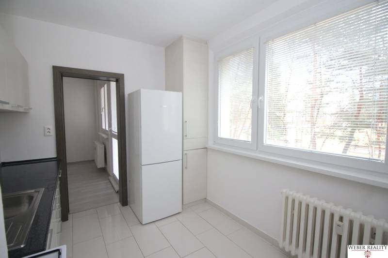 3-izb.byt v Dúbravke (Gallayova ul.) po rekonštrukcii s loggiou - Kuchyňa v 3-izbovom byte s veľkými oknami, chladničkou a svetlou dlažbou.