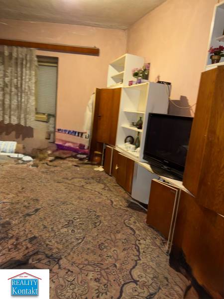 Predáme rodinný dom- Šurany, širšie centrum.  - Izba v rodinnom dome s kobercom, poličkami, televízorom a závesmi.