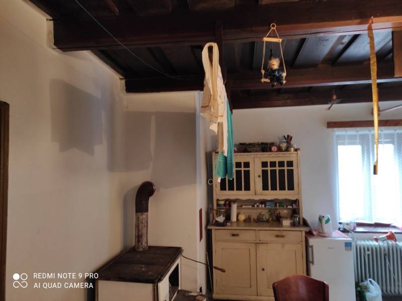 ČREMOŠNÉ-chalupa na pozemku 700m2   - Vidiecka kuchyňa s dreveným stropom a sporákom. Skrinka na druhej strane miestnosti.