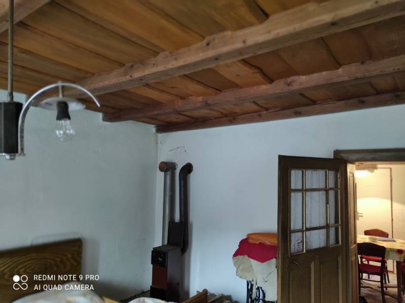 ČREMOŠNÉ-chalupa na pozemku 700m2   - Interiér vidieckeho rodinného domu s dreveným stropom a pieckou na vykurovanie.