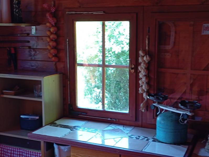 TURANY- krásna chata na pozemku 700m2 - Interiér drevenej chatky so starožitnou váhou, kuchynským kútikom a výhľadom na zeleň.