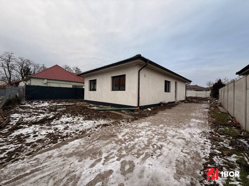 EXKLUZÍVNA SKOLAUDOVANÁ NOVOSTAVBA 4-IZB. RD Z KVALITNÝCH MATERIÁLOV - Rodinný dom v Senci s neudržiavaným zasneženým pozemkom a betónovým chodníkom.