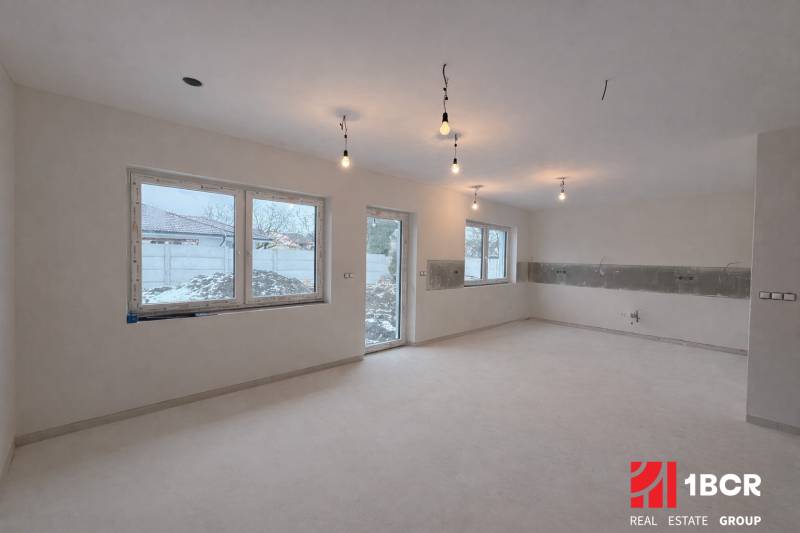 EXKLUZÍVNA SKOLAUDOVANÁ NOVOSTAVBA 4-IZB. RD Z KVALITNÝCH MATERIÁLOV - Interiér v Rodinnom dome so svetlou podlahou a veľkými oknami, bez nábytku.