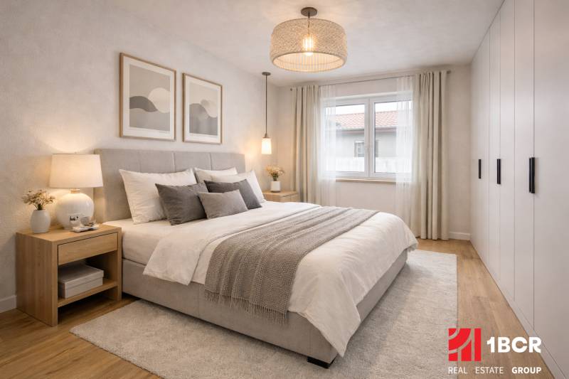 EXKLUZÍVNA SKOLAUDOVANÁ NOVOSTAVBA 4-IZB. RD Z KVALITNÝCH MATERIÁLOV - Svetlá spálňa s veľkou posteľou, nočnými stolíkmi a podlahou s dreveným dekorom v rodinnom dome.