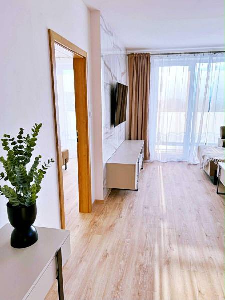 NADŠTANDARDNÝ 3-IZBOVÝ BYT NA PRENÁJOM | Byty Solivarská, Prešov - Interiér 3-izbového bytu s podlahou s dreveným dekorom, TV a závesmi.